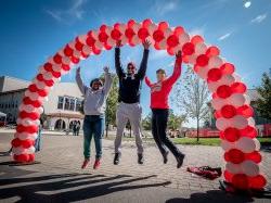 alumni jumping under balloon arch
