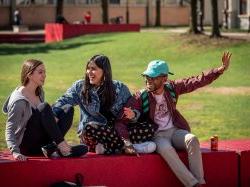 Three students happy, sitting in the quad