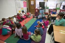 孩子们坐在教室地板上听老师讲课.