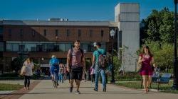 Students walking along the path in front of the CELS building on a sunny day.