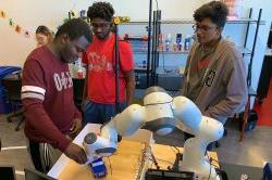 students using a robotic arm in the CRoSS lab