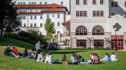 A teacher standing and students sitting on grass at Montclair State University Feliciano School of Business at Spring